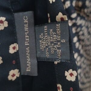 A size 6 black circle skirt. It has cream flowers on the skirt with red centers.